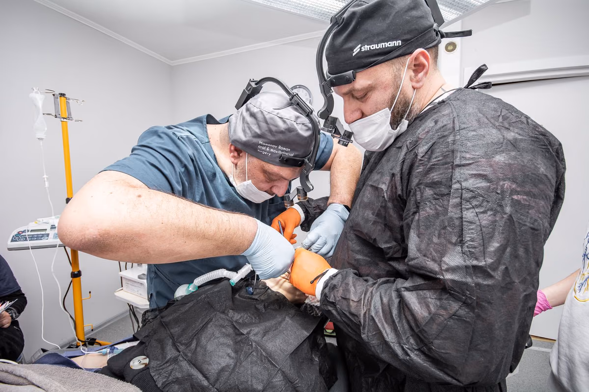 Two oral surgeons working together during an implant procedure in a modern operating room, the reality behind full-arch treatment.