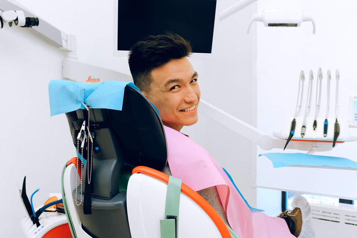 A smiling man seated in a dental chair in a modern Kuala Lumpur clinic, the consultation where a dental implant cost is confirmed after examination.
