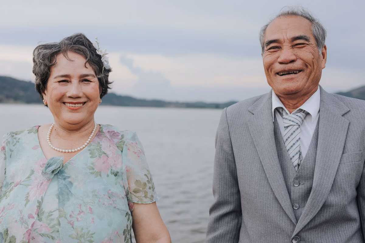 A smiling older couple standing together outdoors, the age group most often considering full-mouth dental implants in Malaysia.