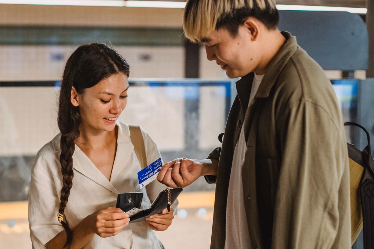 A young couple checking a wallet and card together, weighing whether a lower-priced dental implant quote in Malaysia is worth taking.