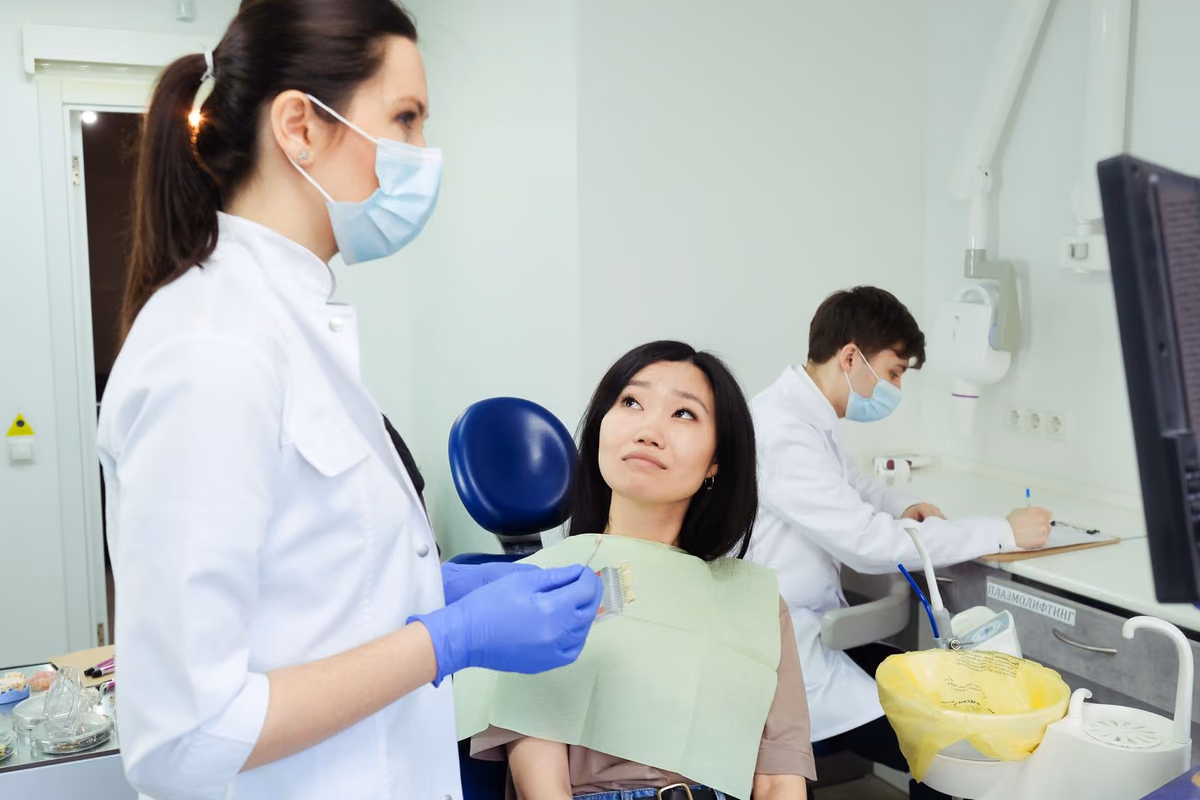 A patient seated in the dental chair discussing orthodontic options with her dentist, the appointment where Invisalign and braces are compared.