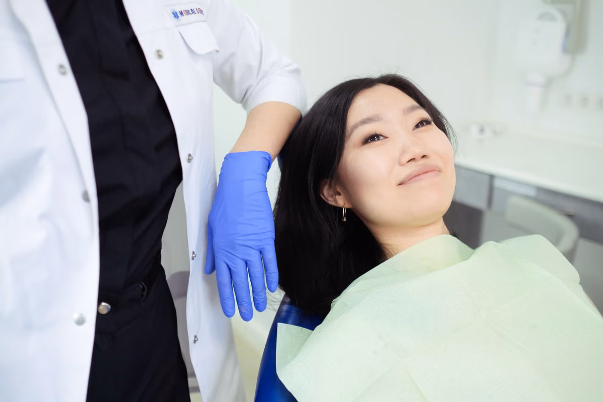 A patient smiling in the dental chair after treatment, the result Malaysians search for as invisible braces, clear aligners or aligner gigi.