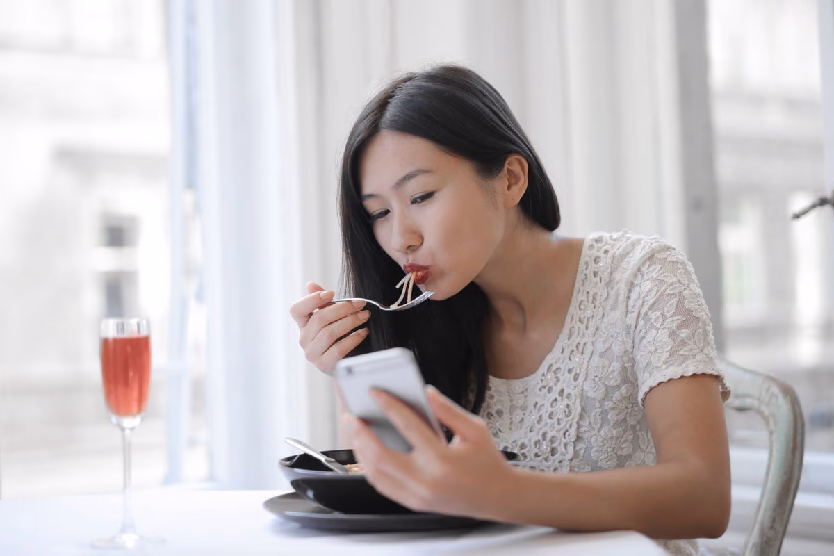 A woman eating a meal out, the everyday freedom removable aligners allow and fixed braces restrict with hard or sticky food.