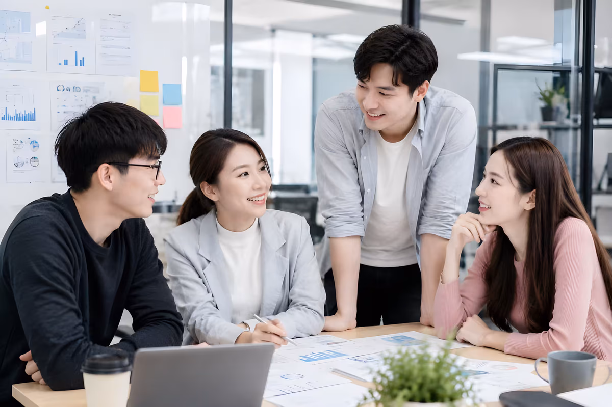 Office colleagues reviewing charts and documents during a team meeting, representing companies exploring corporate dental benefits with Lau Dental Sri Petaling.